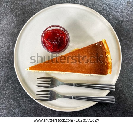 
Sweetmeat. Top view of cheese cake there was strawberry jam and 2 forks placed on the cake plate. A dessert plate of a couple who sat together at the coffee shop. New york cheesecake picture.