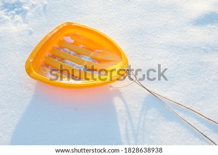 Yellow sled with a rope on white snow