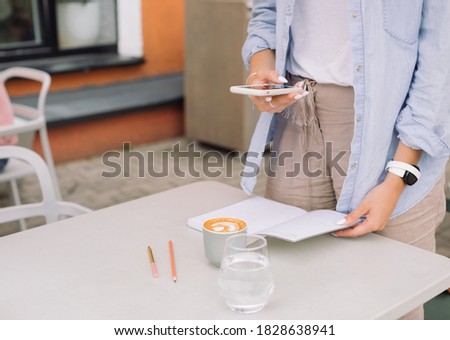 Close up of young woman in casual clothes making photos in cafe. Creating visual content concept.