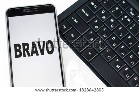 BRAVO text on the phone screen that lies on the laptop keyboard. Business concept