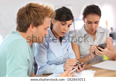 Young people using smartphones in office