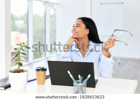 Smiling pretty businesswoman posing at her desk in a bright modern office with copy space. business success,  break time concept Royalty-Free Stock Photo #1828653623