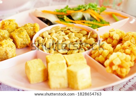 Peanuts, roasted and salted a snack. Placed on a pink plate with different side dishes
