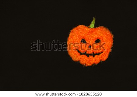 Pumpkin layout for Halloween on a black background with orange sequins. Decorative composition for a holiday. The view from the top. Orange pumpkin with a green tail. Copy space