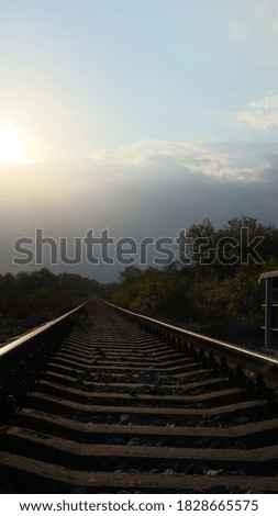 
railway rails with sleepers extending into the distance at sunset