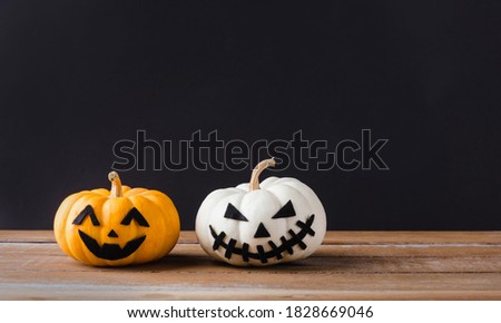 Funny Halloween day party concept ghost pumpkins head jack lantern scary smile on wooden table and black background, studio shot isolated, Holiday decoration