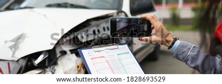 Insurance agent takes pictures of crashed car on his smartphone and fills out the insurance. Insurance agent services concept