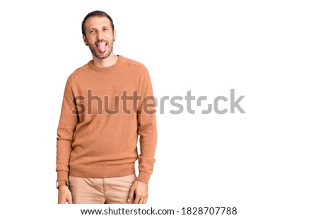 Young handsome man wearing casual clothes sticking tongue out happy with funny expression. emotion concept. 