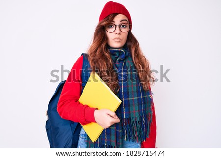 Young beautiful woman wearing winter scarf and student backpack holding book thinking attitude and sober expression looking self confident 