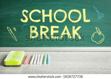 Text School Break and drawings on green chalkboard near table. Seasonal holidays