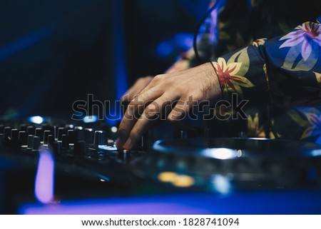 Dj plays music on party in night club.Professional disc jockey playing musical tracks on entertainment event in the club.Djs hands mixing songs on sound mixer on stage in musical hall.Hand of musician