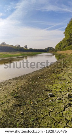 photo of a dried up river.  near the forest.  with clouds in the sky.  green blue