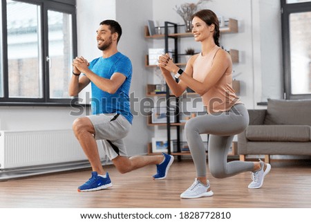 sport, fitness, lifestyle and people concept - smiling man and woman exercising and doing squats in low lunge at home Royalty-Free Stock Photo #1828772810