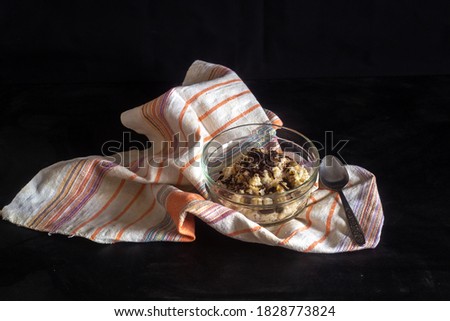 Breakfast. Oatmeal in milk with chocolate chips in a glass bowl. On a dark background with a striped linen napkin