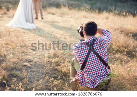 wedding professional photographer takes pictures of the bride and groom in nature on the sunset, man photographer in action