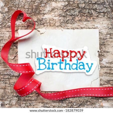 Happy birthday text and ribbon with heart on textured wood background