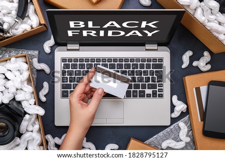 Black Friday concept. Female hand holding a credit card and shopping online through laptop. Computer is surrounded by cardboard boxes with protective foam pads and electronic products inside. Flat lay Royalty-Free Stock Photo #1828795127