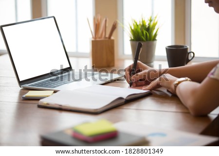 
Cropped shot of Business women are using a tablet showing a white screen to put your text and pictures with a pen working on a table beside the window.