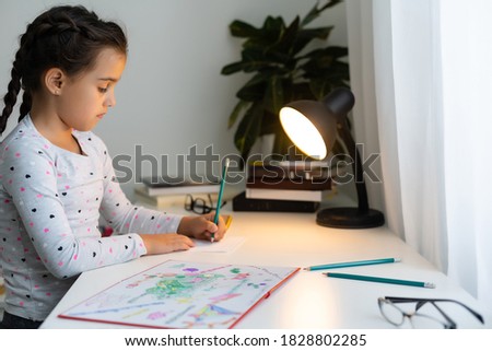 Child little girl laughing, painting colorful pencils at her playtable
