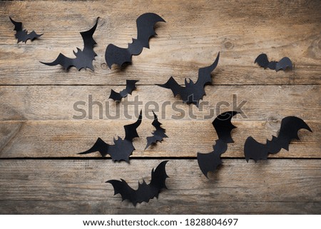Paper bats on wooden background, flat lay. Halloween decor