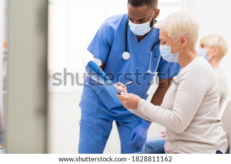 Covid-19, Coronavirus Vaccination. Senior Patient Woman Signing Papers With Doctor Before Corona Virus Vaccine Injection In Hospital Waiting-Room. Covid Medical Immunization Campaign Concept