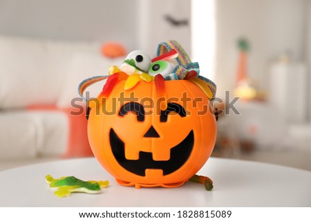 Halloween trick or treat bucket with different sweets on white table indoors