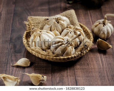Garlic Cloves and Bulb in vintage wooden plate. Selective focus. Brown wood textured surface
