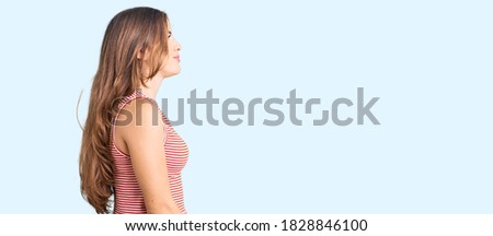 Beautiful caucasian young woman wearing casual clothes looking to side, relax profile pose with natural face with confident smile. 