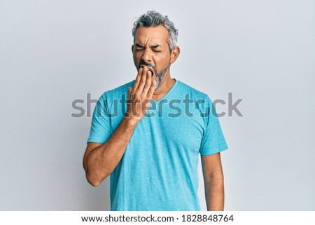 Middle age grey-haired man wearing casual clothes bored yawning tired covering mouth with hand. restless and sleepiness. 