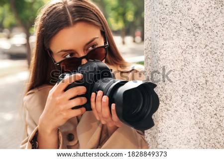 Private detective with camera spying near building on city street