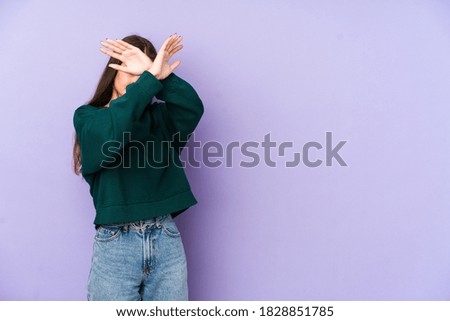 Young caucasian woman isolated on purple background keeping two arms crossed, denial concept.