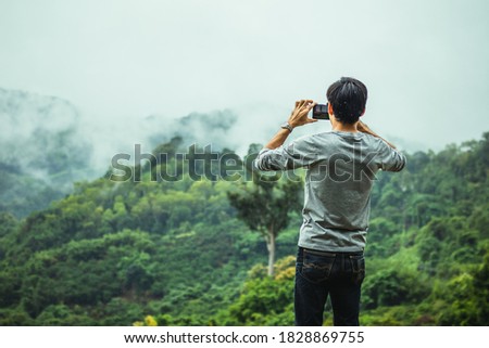 Asian male tourists take pictures of mountain landscapes after rain in northern Thailand.