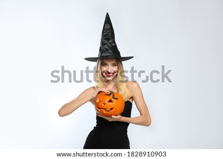 Beautiful woman in witch costume with jack o'lantern on white background. Halloween party