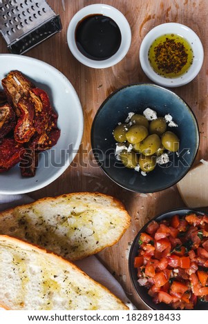 Tomatoe salsa, olives, olive oil and balsamic glaze in small bowls on the wooden board. Italian snack flat lay