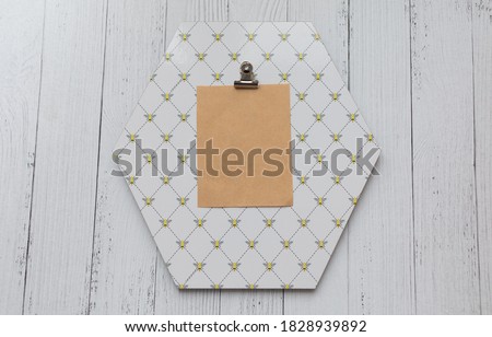 blank piece of papaer on octagon shaped note board white wooden background. Bee pattern note board. Stationery scene.