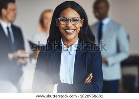 Smiling young African businesswoman standing in an office with a diverse group of colleagues standing in the background