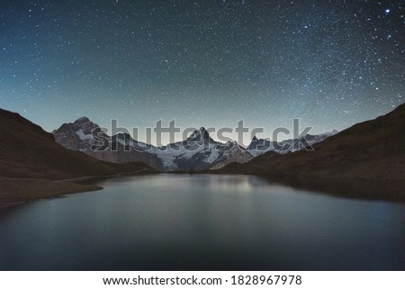 Incredible night view of Bachalpsee lake in Swiss Alps mountains. Snowy peaks of Wetterhorn, Mittelhorn and Rosenhorn on background. Grindelwald valley, Switzerland. Landscape astrophotography Royalty-Free Stock Photo #1828967978