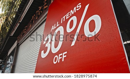 White text on a red banner standing on the street with the inscription 30% off