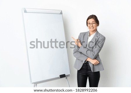 Young Ireland woman isolated on white background giving a presentation on white board and pointing to the side