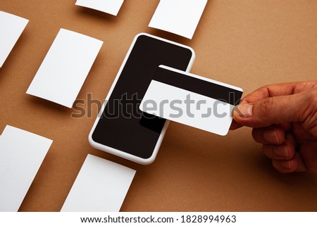 Device with blank screen floating above brown background. Phone and cards. Office styled, modern mockup for advertising, image or text. Blank white copyspace for design, business and finance concept.