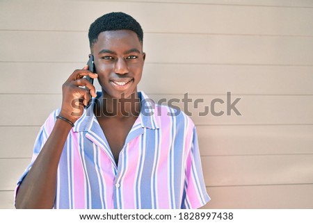 Young african american man smiling happy tallking on the smartphone at street of city.