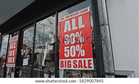 Red sign hanging on the door of the institution with a glass window with the inscription big sale
