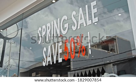 White and red text on a glass window with the inscription spring sale save 50