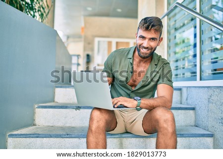 Young hispanic man smiling happy using laptop sitting on stairs