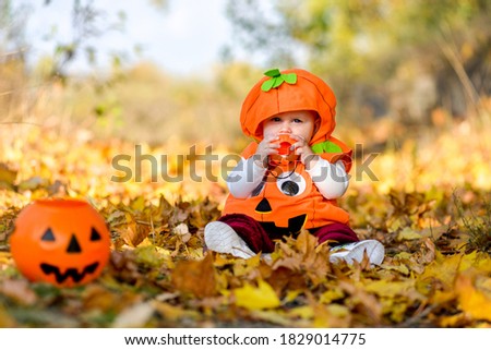 Child in pumpkin suit on background of autumn leaves