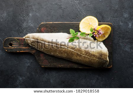 Skinned white sea fish cod fillet with ingredients for simple homemade healthy comfort food. Top view. On a dark background. Flat lay