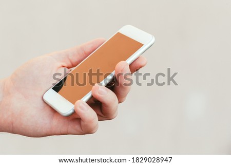 male hands holding a modern phone mock-up for your text message or information content, on a light blurred background