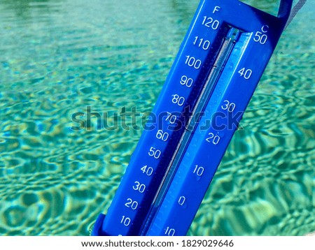 A closeup shot of a blue thermometer near pool water
