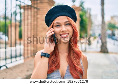 Young redhead girl wearing french style talking on the smartphone at the city.