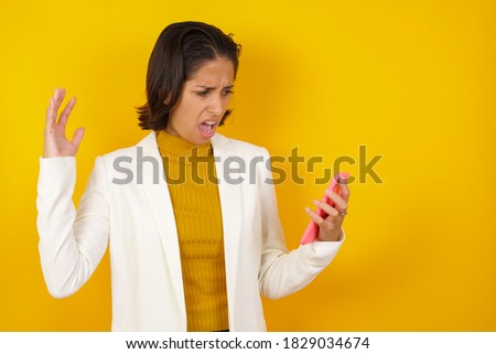 Excited woman showing smartohone blank screen, blinking eye and doing ok sign with hand. Studio shot of shocked girl holding smartphone with blank screen. Advertisement concept.